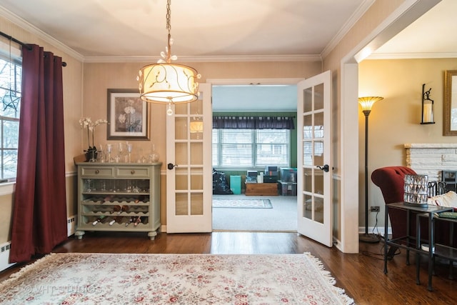 entryway with french doors, a fireplace, crown molding, and wood finished floors