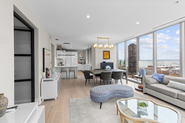 living area with light wood finished floors, expansive windows, a chandelier, and recessed lighting