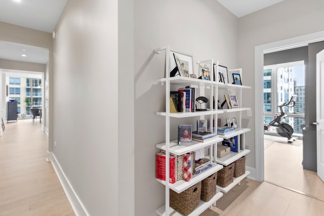 hallway featuring recessed lighting, plenty of natural light, baseboards, and wood finished floors