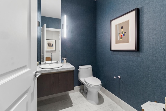 bathroom with toilet, marble finish floor, baseboards, and vanity