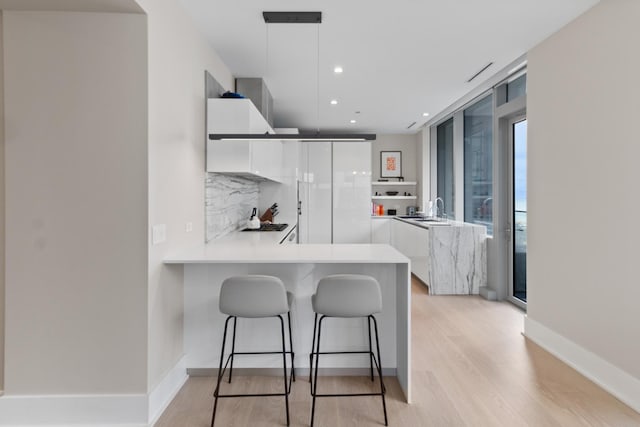 kitchen featuring white cabinetry, a sink, a peninsula, and modern cabinets