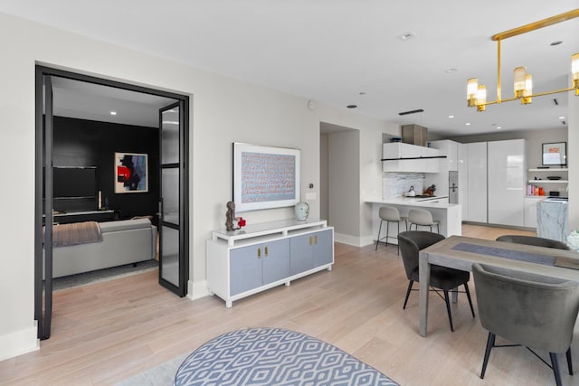 dining room featuring baseboards, recessed lighting, light wood-type flooring, and an inviting chandelier