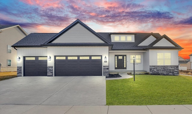 modern farmhouse style home with a shingled roof, a lawn, driveway, stone siding, and an attached garage