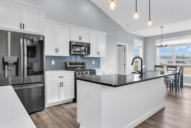 kitchen with decorative backsplash, appliances with stainless steel finishes, wood finished floors, white cabinetry, and a sink