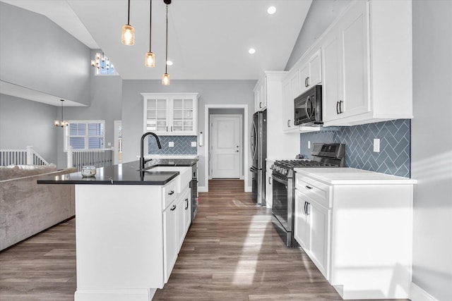 kitchen with dark wood finished floors, open floor plan, a center island with sink, white cabinets, and stainless steel appliances