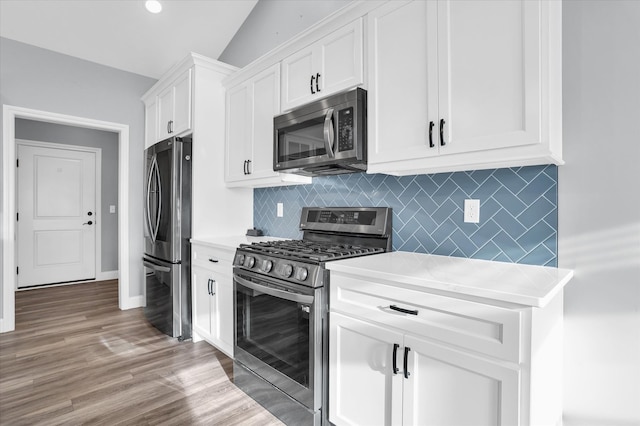 kitchen with tasteful backsplash, light wood-style floors, appliances with stainless steel finishes, white cabinets, and light countertops