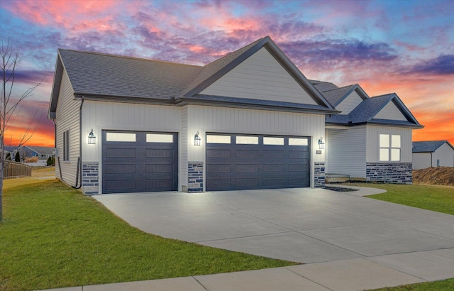 view of front of property with driveway, a front lawn, stone siding, roof with shingles, and an attached garage