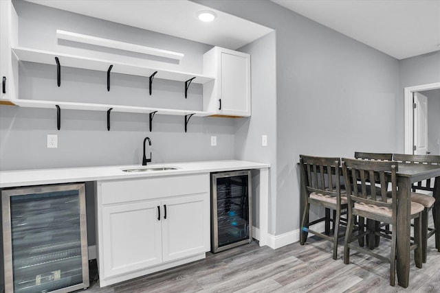 bar with a sink, wine cooler, and light wood-style floors