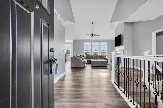 interior space with a ceiling fan, visible vents, wood finished floors, baseboards, and a towering ceiling