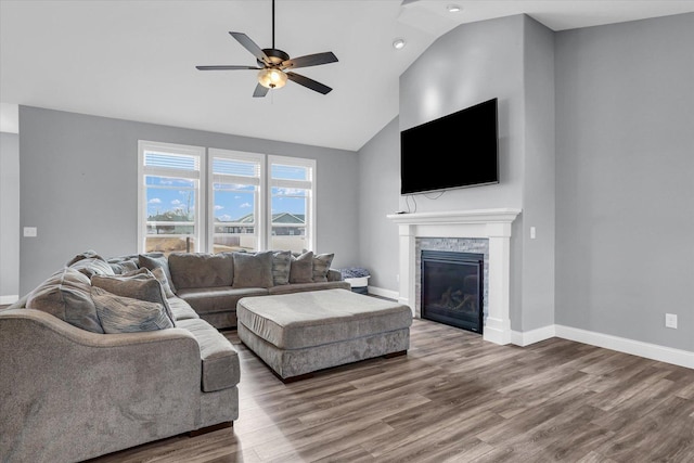 living area featuring baseboards, a ceiling fan, wood finished floors, and a fireplace