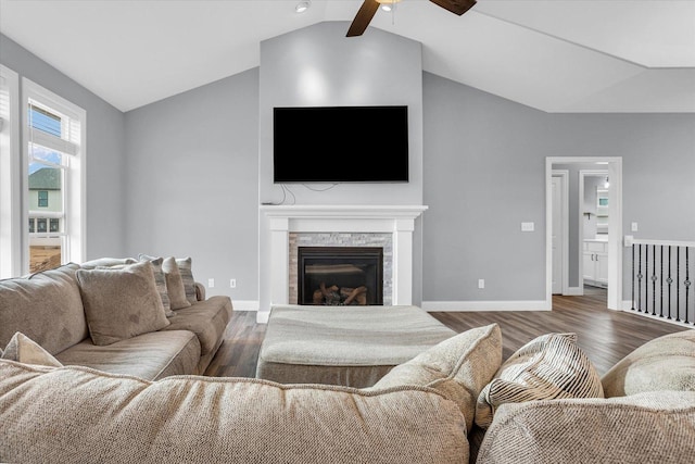 living room with a stone fireplace, baseboards, lofted ceiling, and wood finished floors