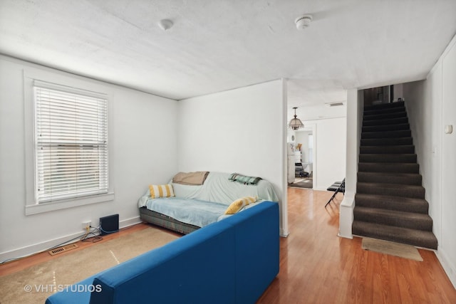 living room with stairs, wood finished floors, visible vents, and baseboards