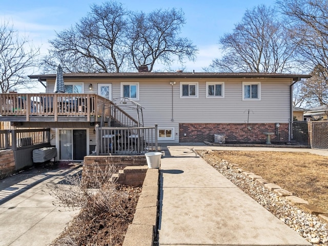 view of front of property with brick siding, fence, stairway, a wooden deck, and a chimney