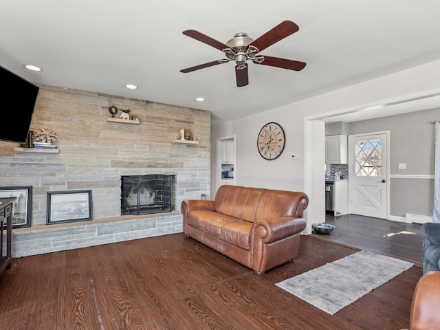 living area featuring recessed lighting, a stone fireplace, baseboard heating, and wood finished floors