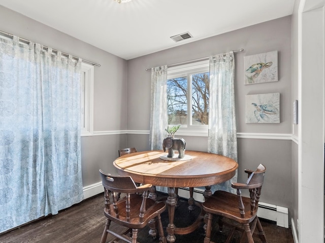 dining room featuring dark wood-style floors, baseboard heating, visible vents, and baseboards