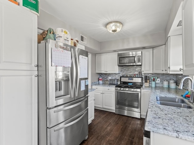 kitchen with stainless steel appliances, a sink, visible vents, white cabinets, and tasteful backsplash