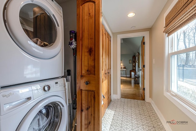 laundry room featuring recessed lighting, laundry area, baseboards, stacked washing maching and dryer, and light floors