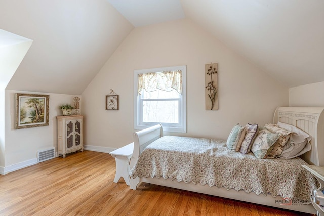 bedroom with visible vents, vaulted ceiling, light wood-style flooring, and baseboards