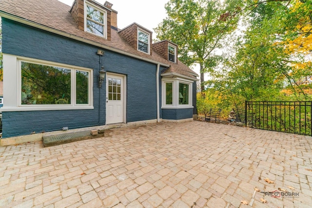 back of property featuring a patio area, a chimney, and fence