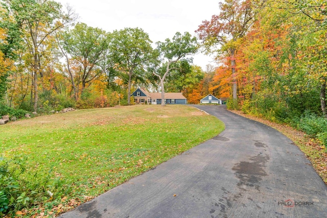 view of front of property featuring a garage, a front yard, and a wooded view