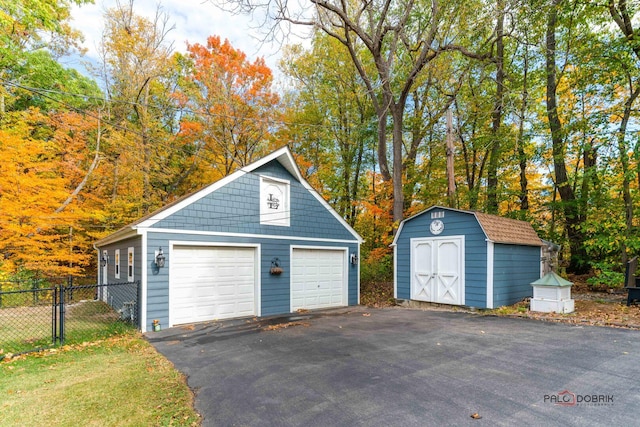 detached garage featuring fence and a shed