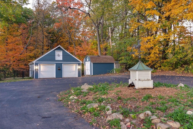 detached garage featuring a storage shed and fence