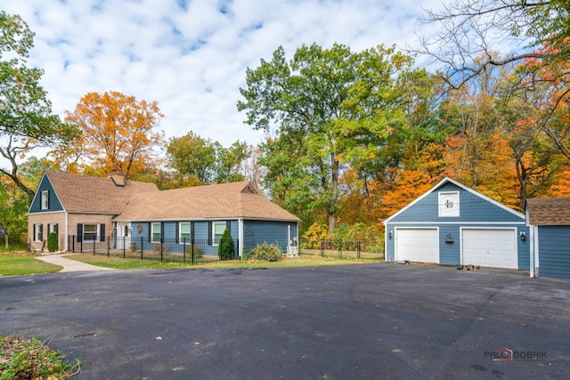 view of front of home with a garage, an outbuilding, and fence