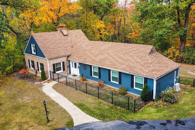 view of front of home with a chimney, roof with shingles, fence, a front yard, and brick siding