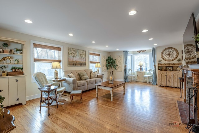 living area featuring baseboards, light wood finished floors, a fireplace, and recessed lighting