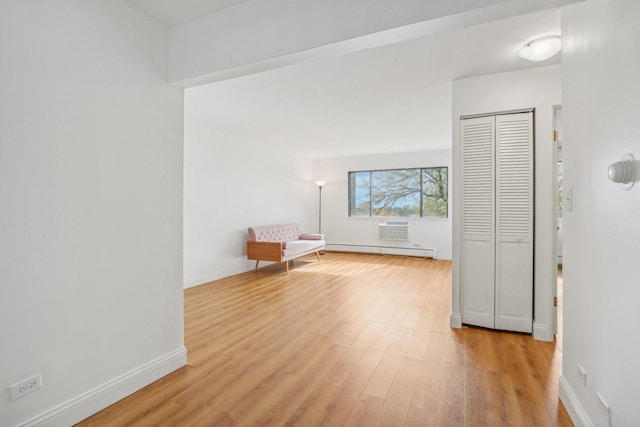 unfurnished room with light wood-style floors, baseboards, and a baseboard heating unit