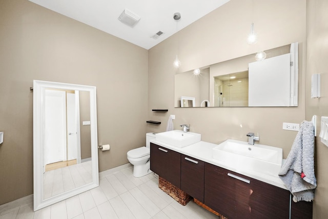 full bath with double vanity, tiled shower, a sink, and toilet