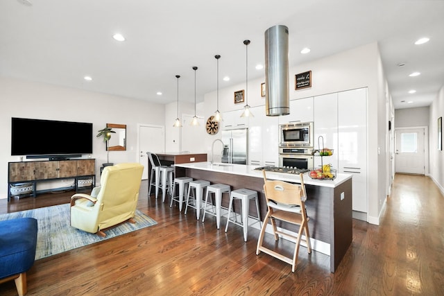 kitchen with a spacious island, modern cabinets, built in appliances, a kitchen bar, and white cabinetry