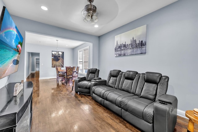 living area with ceiling fan with notable chandelier, recessed lighting, hardwood / wood-style flooring, and baseboards