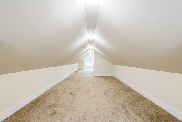 bonus room featuring lofted ceiling, light colored carpet, and baseboards