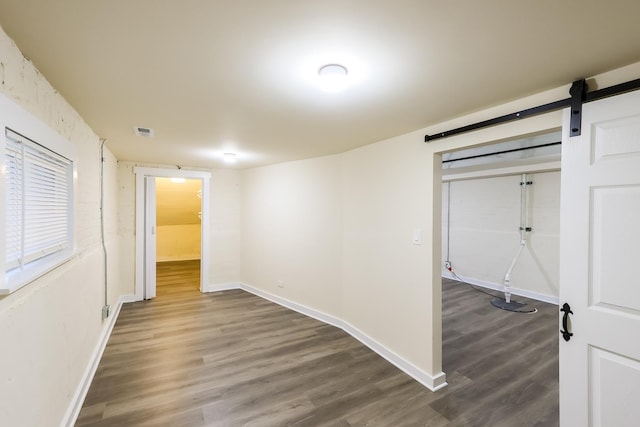 empty room with a barn door, baseboards, and wood finished floors