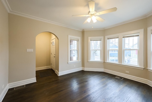 empty room featuring baseboards, crown molding, visible vents, and dark wood-style flooring