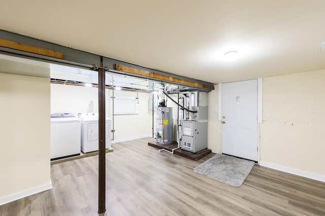 finished basement featuring heating unit, water heater, washer and clothes dryer, and wood finished floors