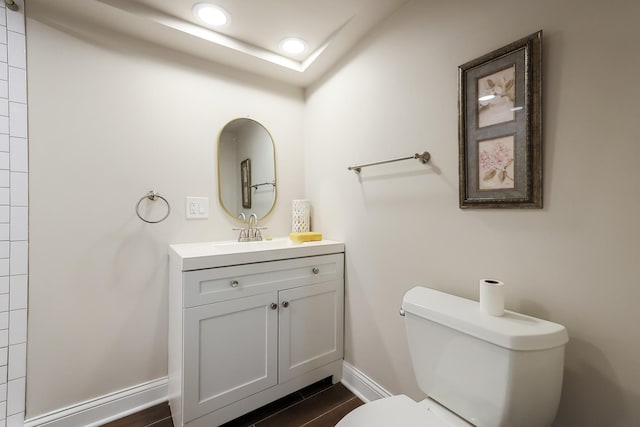 bathroom with recessed lighting, toilet, vanity, wood finished floors, and baseboards