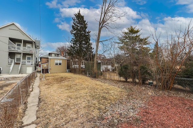 view of yard featuring an outbuilding, a fenced backyard, and a balcony