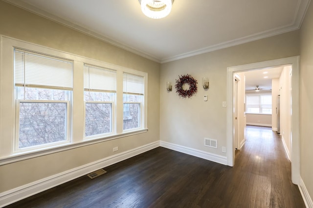 empty room with dark wood-type flooring, visible vents, ornamental molding, and baseboards