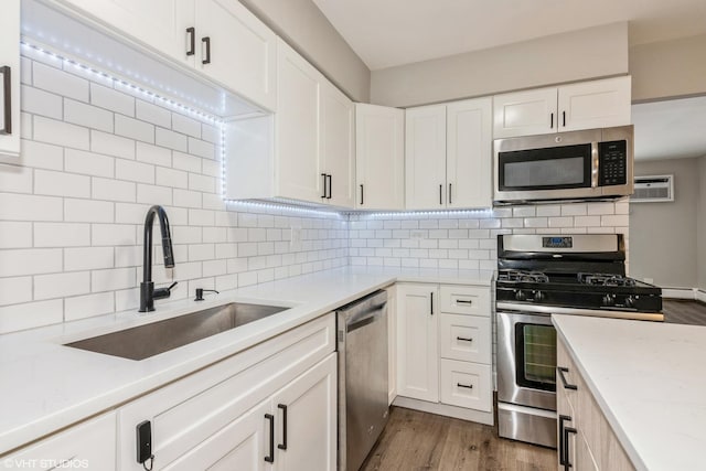 kitchen with stainless steel appliances, dark wood finished floors, a sink, and decorative backsplash