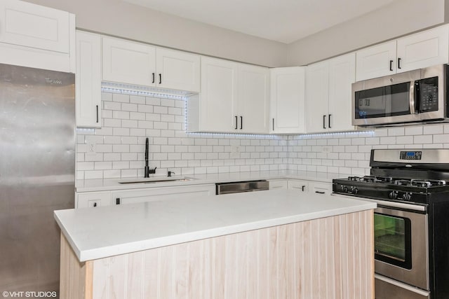 kitchen with stainless steel appliances, a sink, white cabinets, light countertops, and backsplash