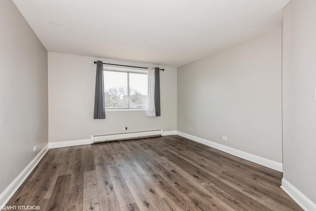 empty room featuring a baseboard heating unit, dark wood finished floors, and baseboards