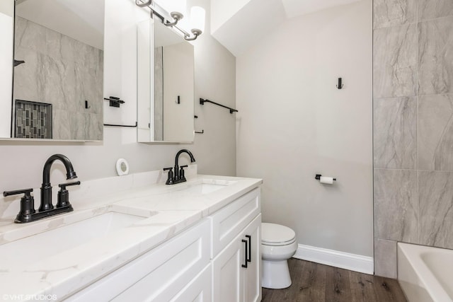 full bathroom featuring a bathtub, a sink, toilet, and wood finished floors