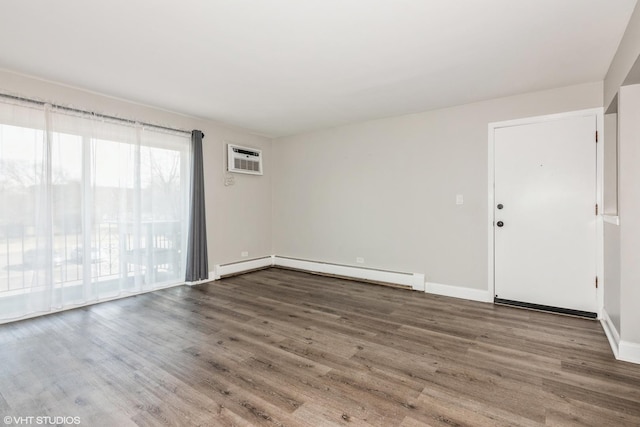 empty room featuring baseboard heating, a wall mounted air conditioner, wood finished floors, and baseboards