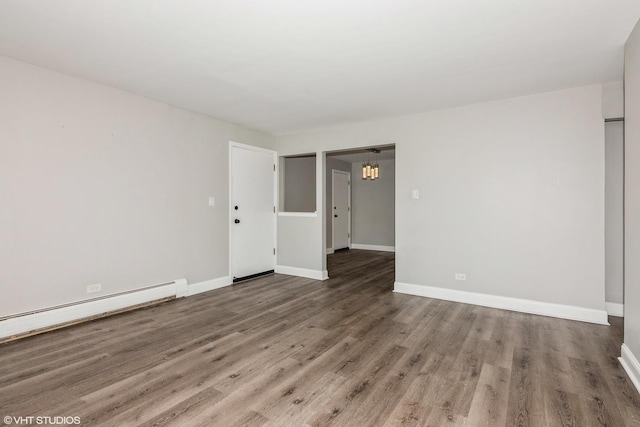 spare room featuring baseboards, baseboard heating, and wood finished floors