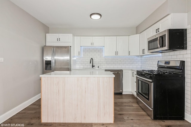 kitchen featuring stainless steel appliances, dark wood-type flooring, a sink, and a center island