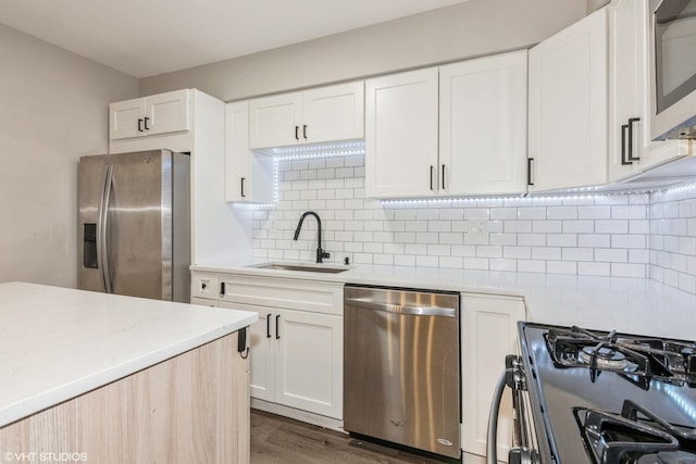 kitchen featuring appliances with stainless steel finishes, light countertops, a sink, and tasteful backsplash