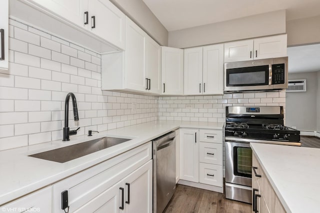 kitchen with dark wood-type flooring, a sink, white cabinets, appliances with stainless steel finishes, and tasteful backsplash