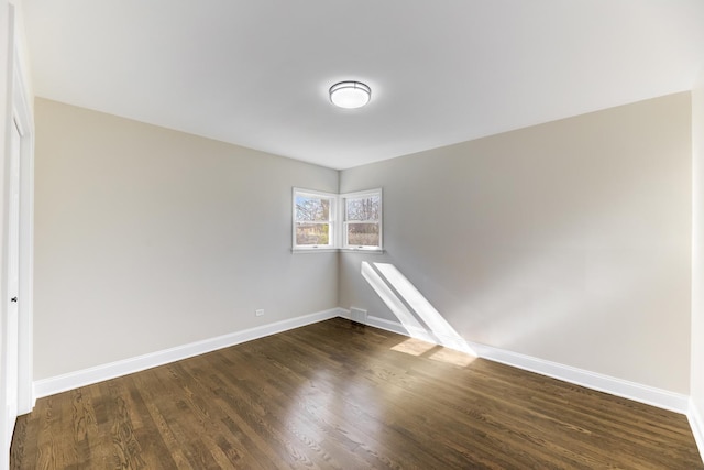 unfurnished room with baseboards and dark wood-style flooring